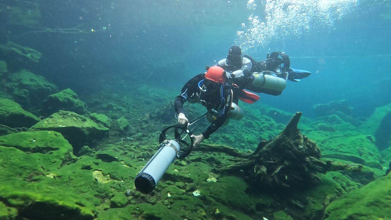 Two cave diver on DPV practicing towing skills for scooter failure
