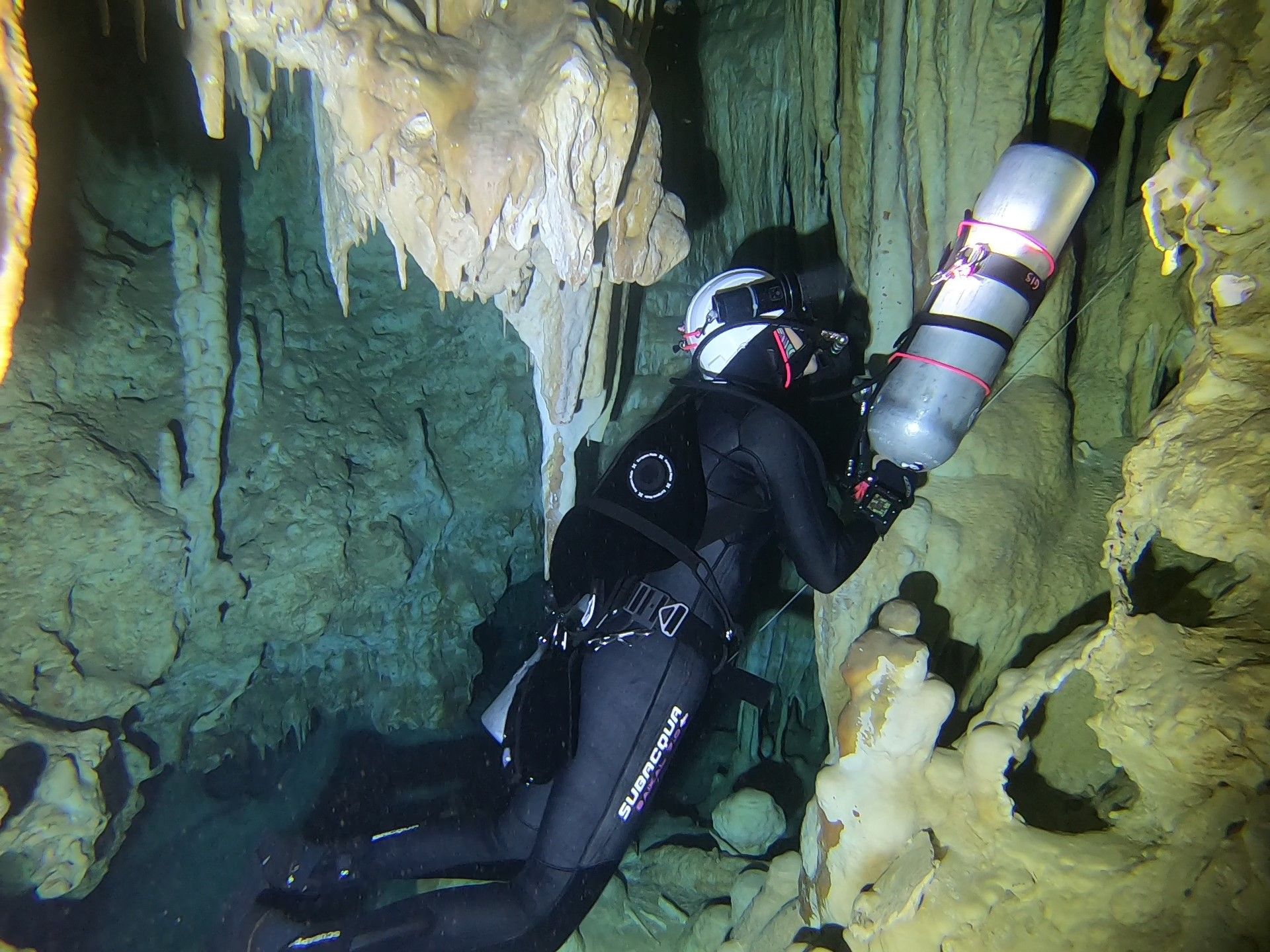 Cave diver passing a restriction with a tank removed